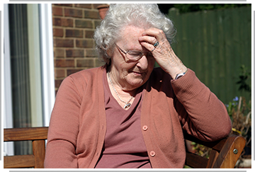 older woman holds forehead in distress