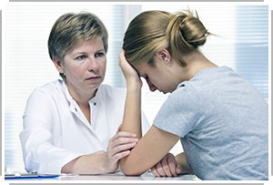 doctor listens to young, upset woman with head in hand