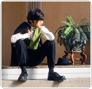 young man in suit, sitting on porch, holding head in hands