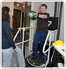 therapist helping boy use Proprio-Balance machine