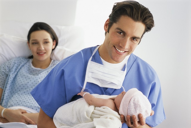 Doctor holding baby while mother watches